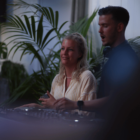 vrouw achter dj tafel met dj rogee op feest